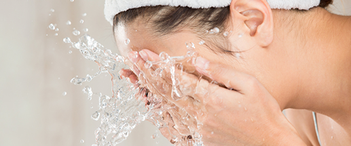 A woman splashing her face with water. Decorative image for the post "Double Cleansing basics and How to do it Right!"