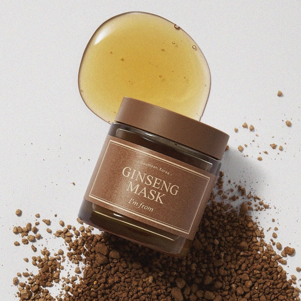 Jar of I'm From Ginseng Mask lying down with a drop of the product and some reddish-brown dirt-like material in the backgound