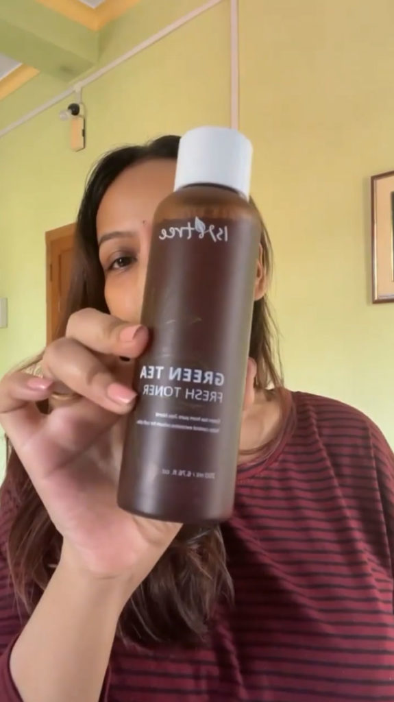 blogger clara gomes holding the isntree green tea fresh toner she used for her hormonal acne